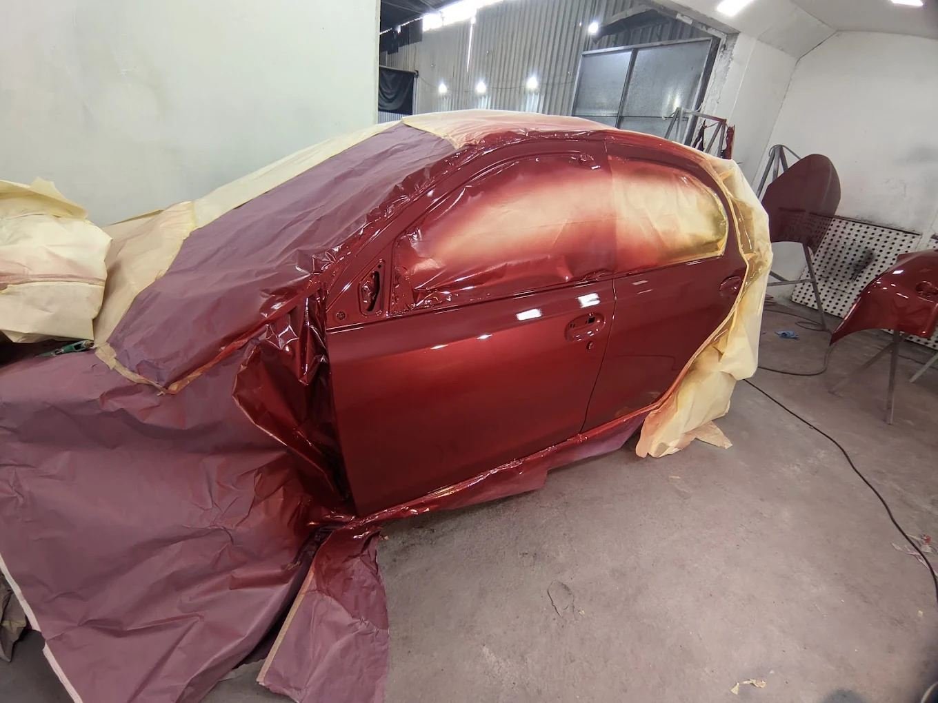 Lateral vermelha recém-pintada com o restante do carro protegido